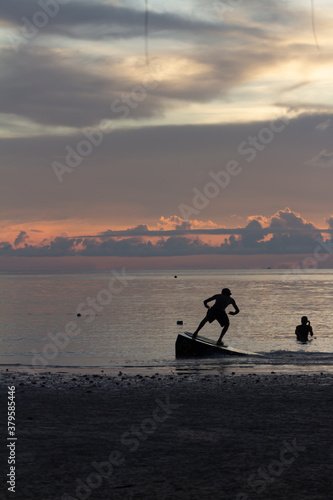 Persona haciendo surf en la playa con atardecer