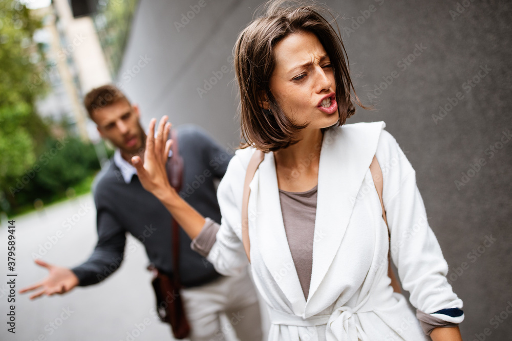 Sad young woman and man outdoor on street having relationship problems