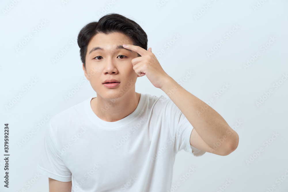 Young attractive man checking his skin and touching wrinkles on his face Young attractive man checking his skin and touching wrinkles on his face