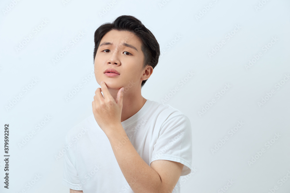 Young handsome man over white background looking confident at the camera smiling with hand raised on chin. Thinking positive.