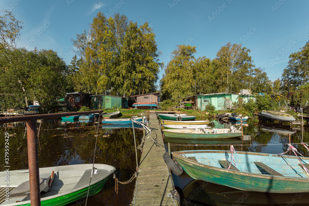 Floating village with small wooden houses and old boats on a sunny day in Russia.