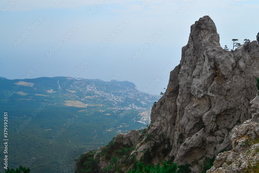 large steep sharp stone rock Ai-petri cliff against the background of Black sea coastline in Crimea, the city below, summer