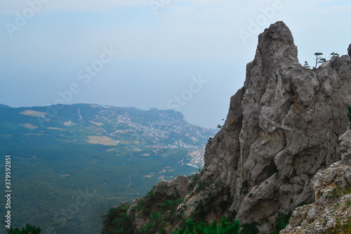 large steep sharp stone rock Ai-petri cliff against the background of Black sea coastline in Crimea, the city below, summer