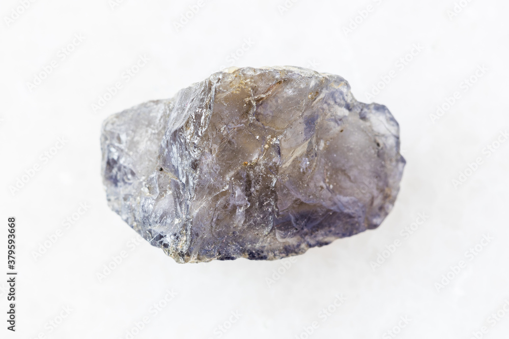 closeup of sample of natural mineral from geological collection - unpolished Cordierite (Iolite) crystal on white marble background from Madagascar closeup of sample of natural mineral from geological collection - unpolished Cordierite (Iolite) crystal on white marble background from Madagascar