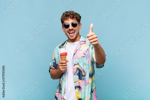 young man feeling proud, carefree, confident and happy, smiling positively with thumbs up. holidays concept