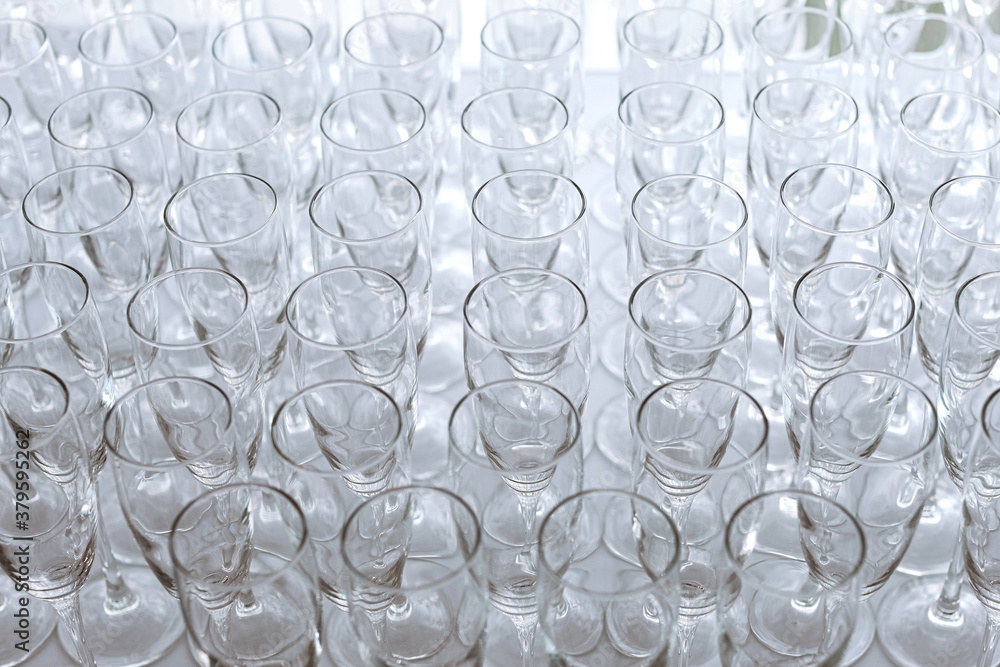 Close up rows of clean glasses for wine and champagne on a rack made the bartender for drinks during the event and celebration. Clean transparent glasses for beverages on the table. Soft focus. Close up rows of clean glasses for wine and champagne on a rack made the bartender for drinks during the event and celebration. Clean transparent glasses for beverages on the table. Soft focus.