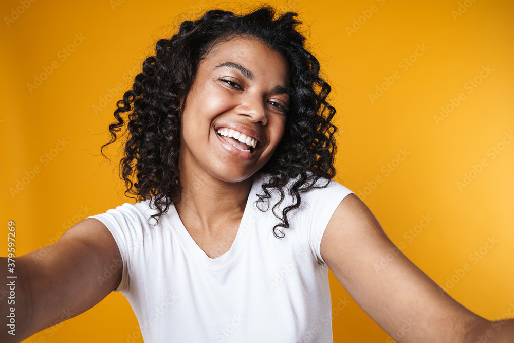 Image of joyful african american girl smiling while taking selfie Image of joyful african american girl smiling while taking selfie