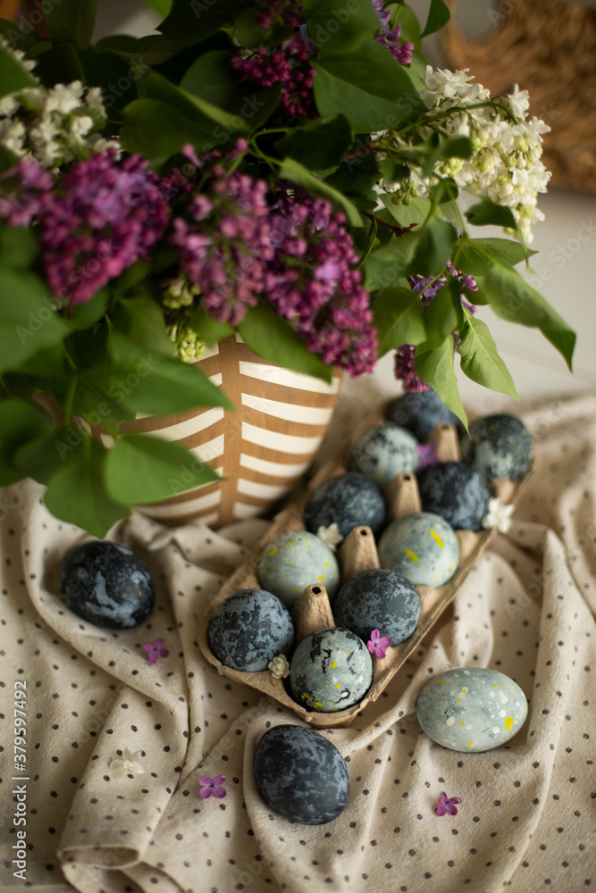 Easter eggs on the table, decorated with lilacs. 