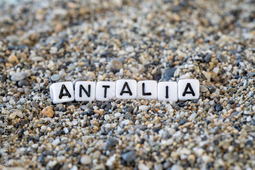 Antalia inscription text with name of the vacation destination city in a still life of the letters layed out on a shore sand stones.