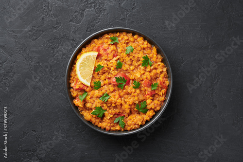 Fotografie Red lentils dal in black bowl on dark slate table top