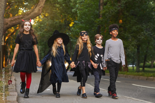 Obraz na plátně Full length portrait of multi-ethnic group of kids walking in street while trick