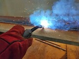 A welder is welding under flux, a type of electrical procedure.  Welding takes place by arc heating between the bare electrodes and the work piece metal.  The welding electrodes are fed continuously b