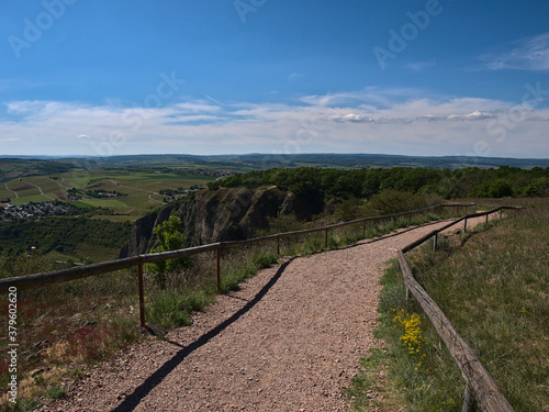 Fenced gravel path on Rotenfels ("red rock"), a rock formation near health resort Bad Kreuznach, Rhineland-Palatinate, Germany with fields and hills in background on a sunny summer day.