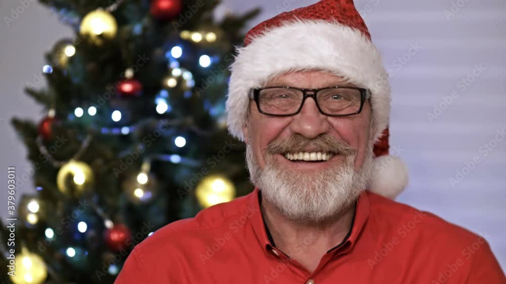 Santa Claus portrait, sitting indoor near decorated xmas tree with lights - Merry Christmas and Happy Holidays Santa Claus portrait, sitting indoor near decorated xmas tree with lights - Merry Christmas and Happy Holidays
