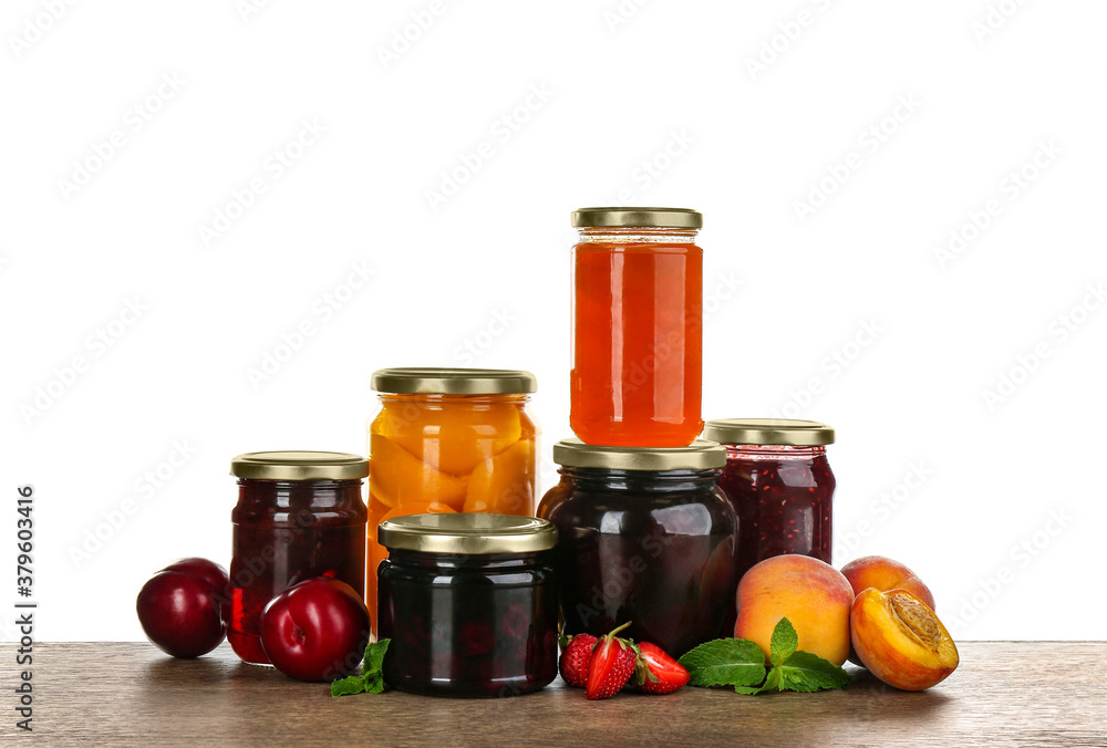 Jars of pickled fruits and jams on grey table Jars of pickled fruits and jams on grey table