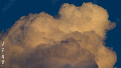 Sommet d'un cumulus de couleur orangée, par-dessus un ciel bleu marine