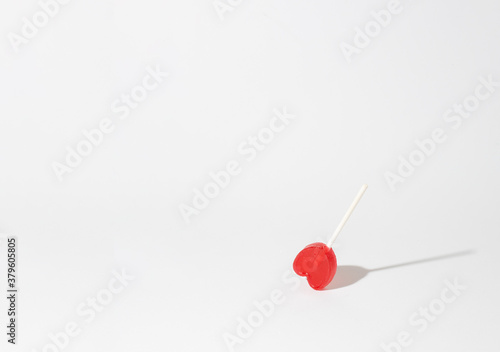 red heart shaped lollipop on white background © robcartorres