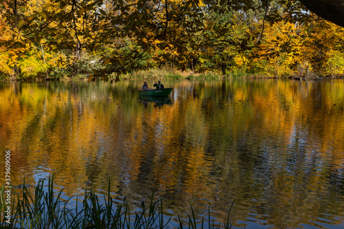 beautiful autumn landscape yellow trees reflected in the water of the lake fishermen catching fish