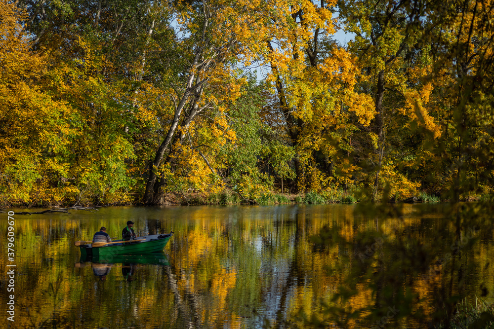 Fototapeta premium beautiful autumn landscape yellow trees reflected in the water of the lake fishermen catching fish