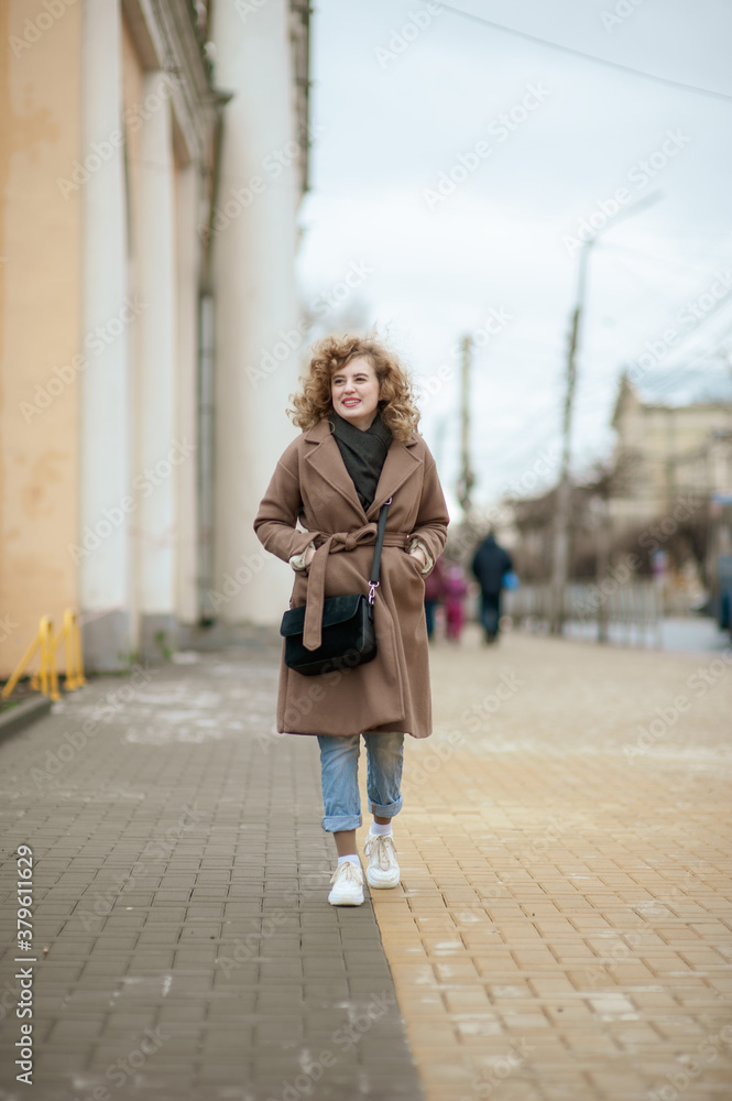 Portrait of a curly-haired young woman who walks the streets of the city