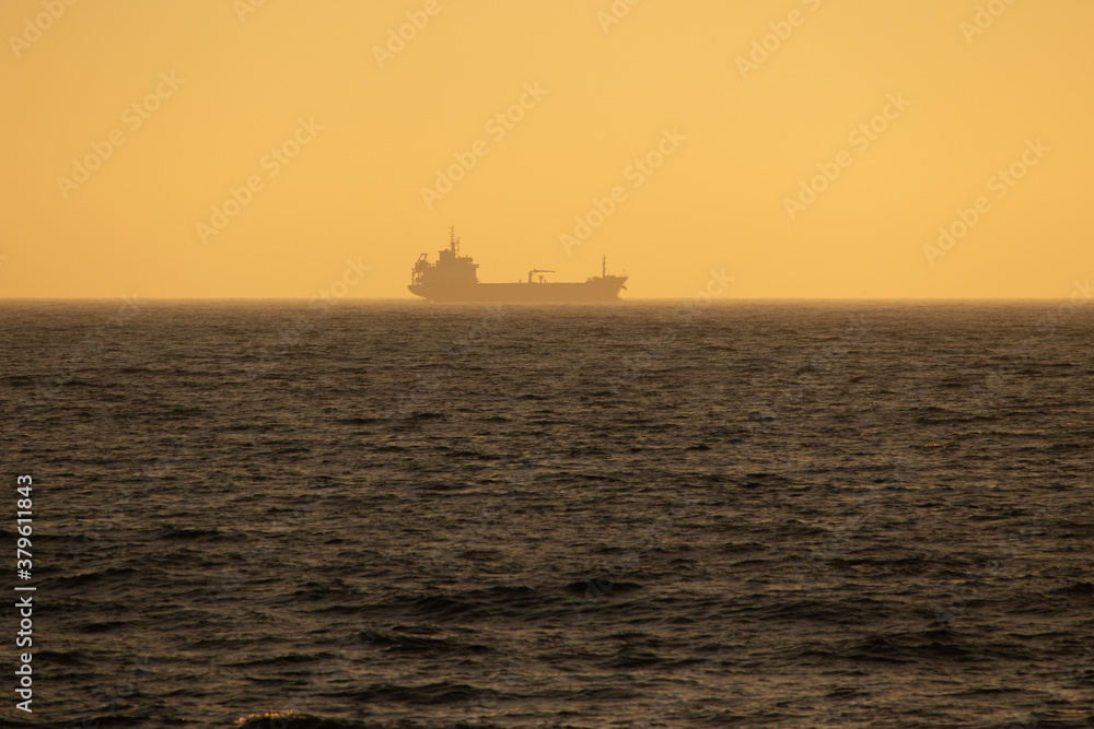Large cargo ship sailing smoothly in the ocean during a wonderful sunset, Portugal
