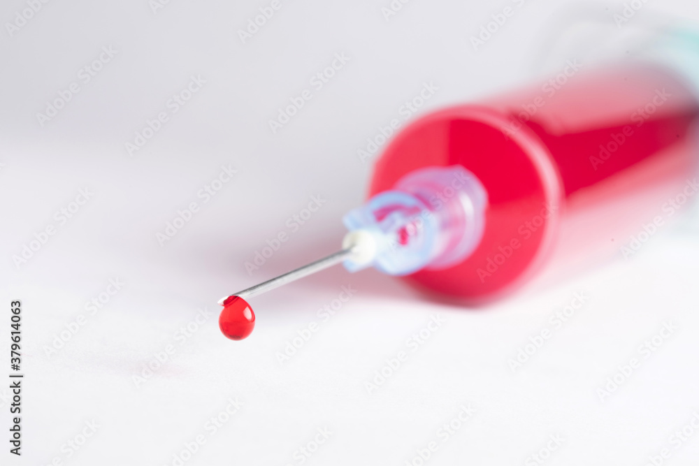 Syringe with a drop of blood at its tip Syringe with a drop of blood at its tip