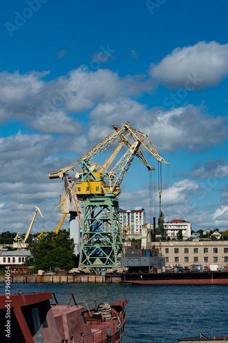 Large ship crane in the seaport. Loading crane at the pier against the background of blue sky with clouds.