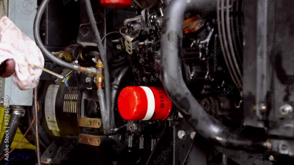 Adult male Caucasian technician hand checks oil on diesel generator by