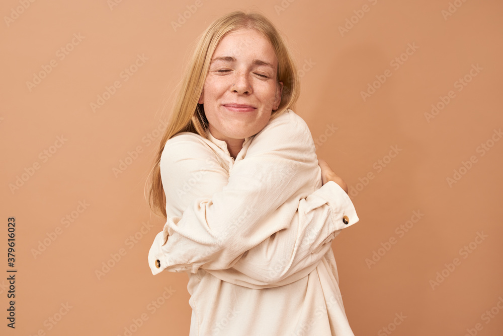 I love myself. Beautiful pleased young blonde female with high esteem hugging herself keeping arms around her body, closing eyes, feeling comfortable and cozy. Joy, tenderness and comfort concept I love myself. Beautiful pleased young blonde female with high esteem hugging herself keeping arms around her body, closing eyes, feeling comfortable and cozy. Joy, tenderness and comfort concept