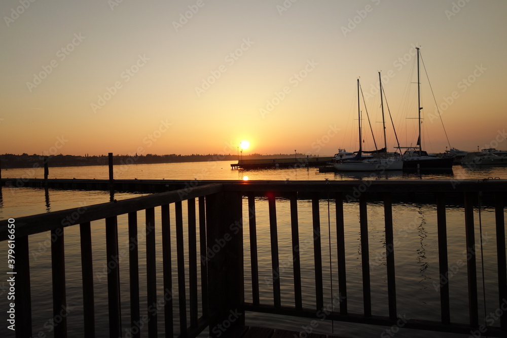 Abenddammerung und Sonnenuntergang  durch Geländer Fotografiert am Jachthafen mit Jachten im Hintergrund