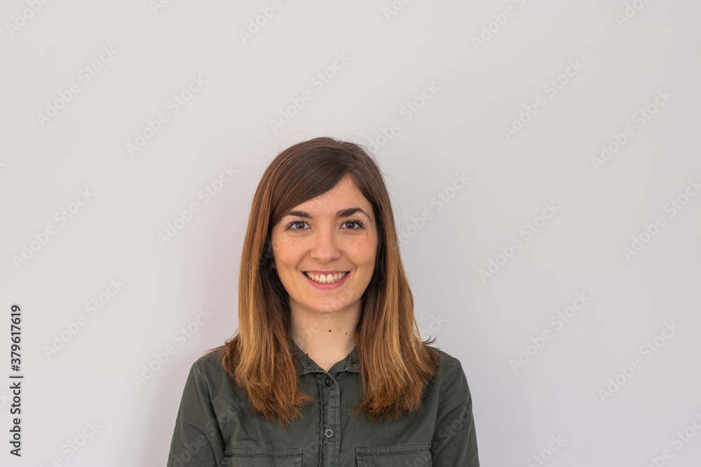 Photo of a young and attractive woman looking corporative with a shirt smiling at the camera, looking professional and ready to do bussiness with a white background