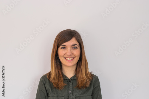 Photo of a young and attractive woman looking corporative with a shirt smiling at the camera, looking professional and ready to do bussiness with a white background