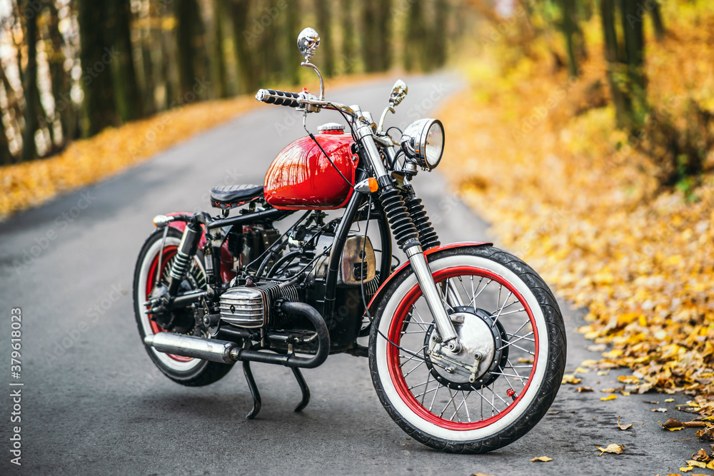 Red custom old fashioned motorcycle on the road in the forest