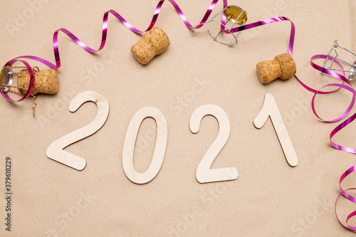 Light wooden 2021 numbers lie on craft paper with champagne corks, muzle and packing tape around photo