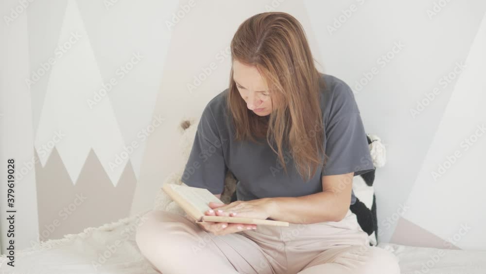 A beautiful woman reads a book on the bed. My mother sat down to read a book while cleaning in the children's room. A beautiful woman reads a book on the bed. My mother sat down to read a book while cleaning in the children's room.