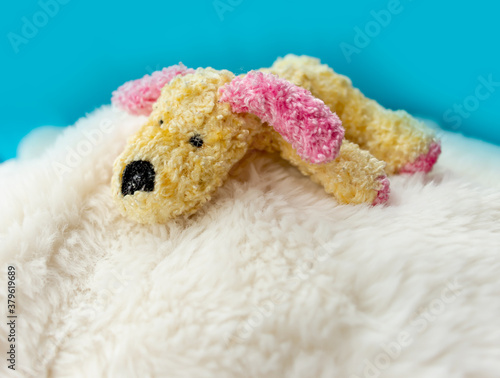 Cute yellow plush puppy toy with pink ears on blue backgorund