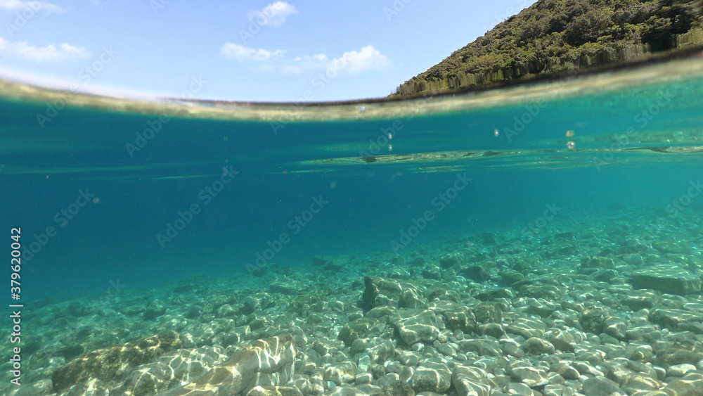 Sea level and underwater photo of beautiful pebble beach of Krovoulia near picturesque village of Frikes, Ithaki island, Ionian, Greece