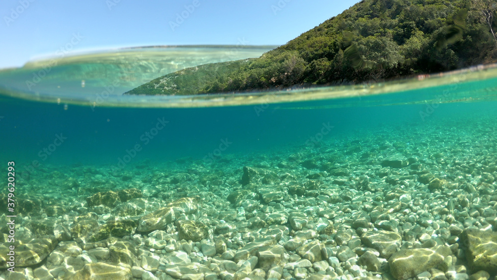 Sea level and underwater photo of beautiful pebble beach of Krovoulia near picturesque village of Frikes, Ithaki island, Ionian, Greece