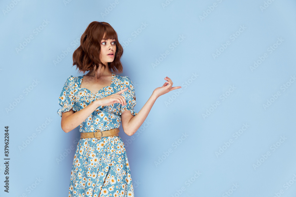 Woman in flower dress looks to the side points fingers to the side fashionable hairstyle Woman in flower dress looks to the side points fingers to the side fashionable hairstyle