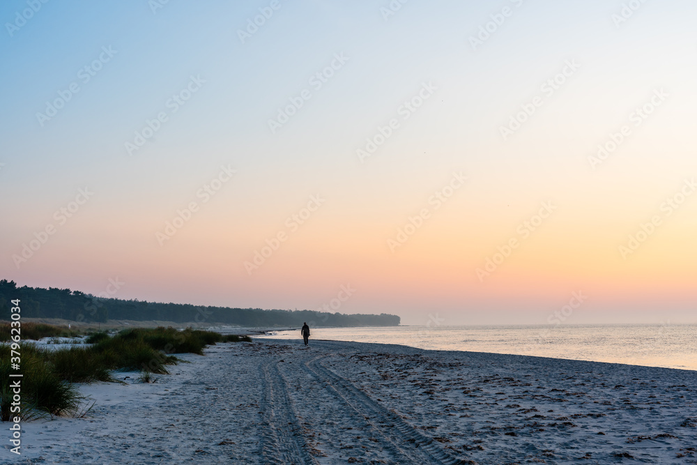 sunrise over the sea with a beach walker