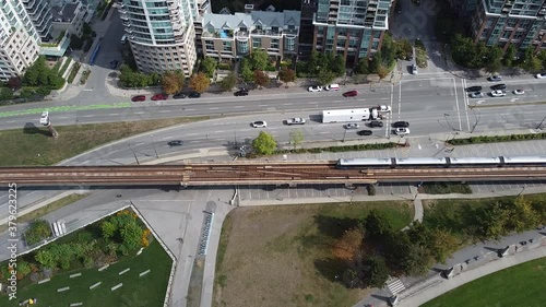 Top down view of subway tracks with train passing, highway and bike tracks