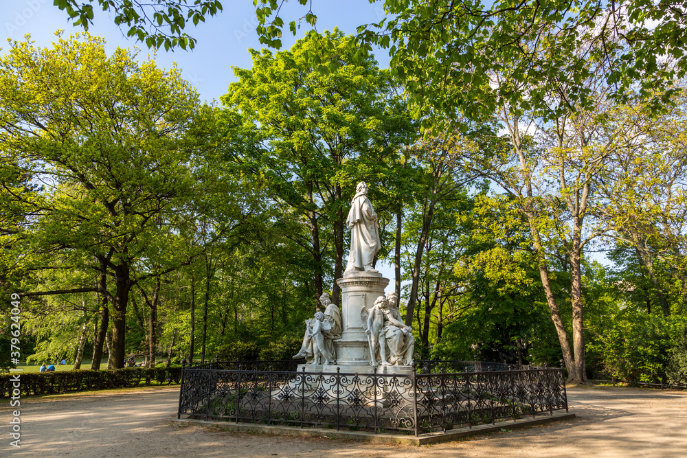 Marble statue in a cemetery park with green trees