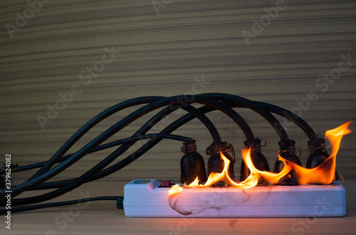 Fotografie On fire multi socket with the connected power strip with a bunch of plugs on woo
