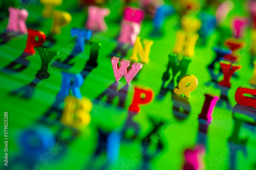 English 3D alphabet on a green background. Focusing on letters in center. Extreme letters of the alphabet are blurred. Three-dimensional Latin letters as a symbol of learning English.
