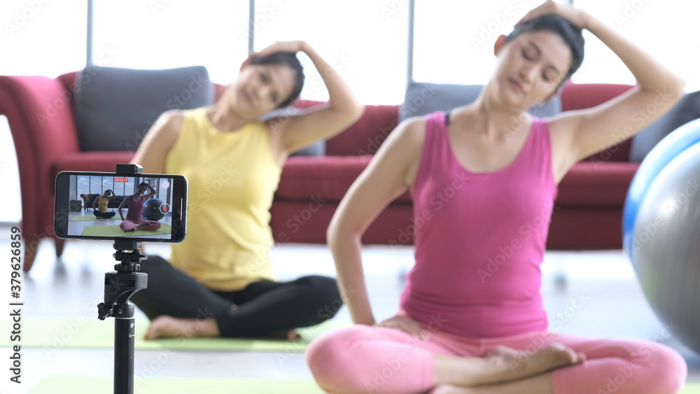 Naklejka premium Young asian couple in sportswear recording video blog yoga training.