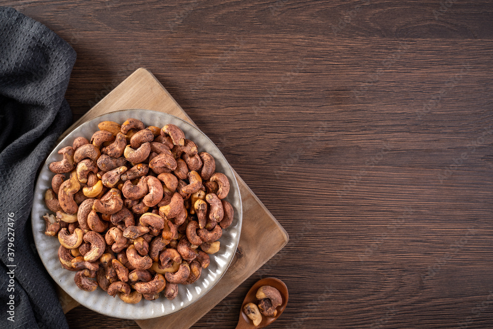 Cashew nuts with peel in a plate on wooden tray and table background, healthy raw food plate. Cashew nuts with peel in a plate on wooden tray and table background, healthy raw food plate.