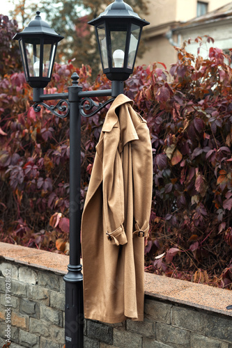 beige coat hanging on a hanger outside in autumn. autumn mood