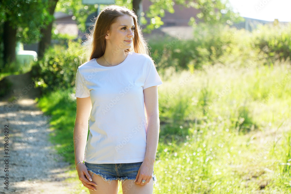 Junge Frau trägt T-Shirt in Weiß mit Textfreiraum oder Copy Space für Bedruck, Design oder Logo Junge Frau trägt T-Shirt in Weiß mit Textfreiraum oder Copy Space für Bedruck, Design oder Logo