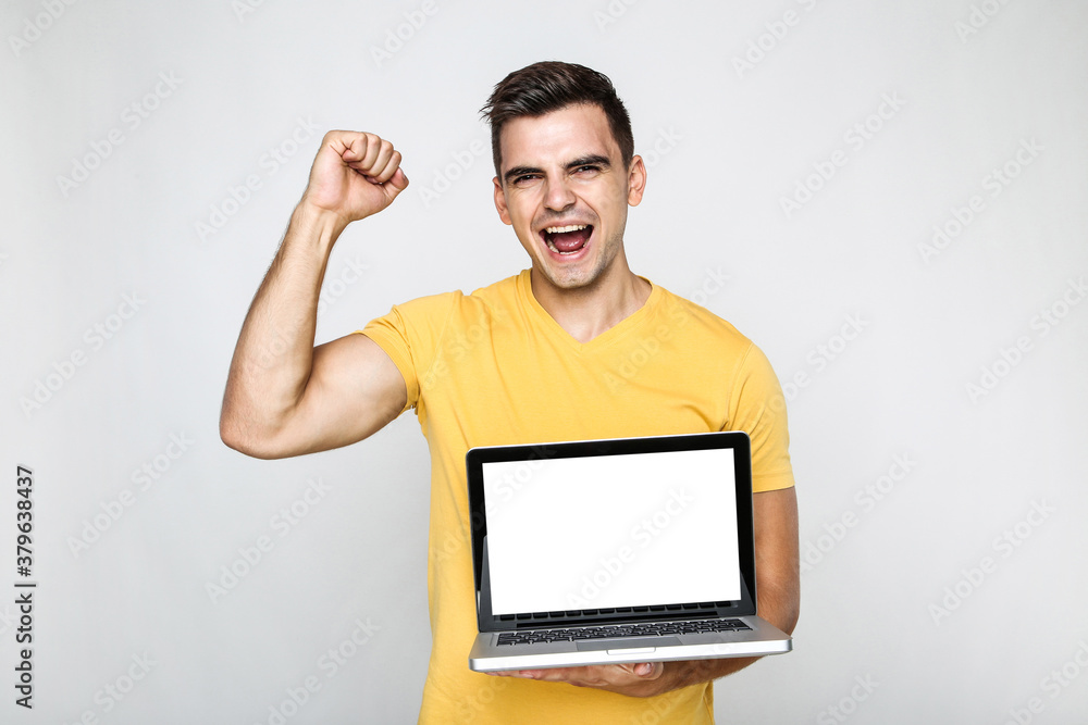 Young emotional man with computer laptop on grey background Young emotional man with computer laptop on grey background