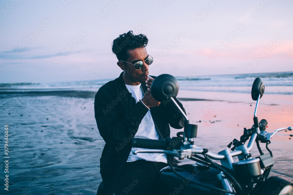 Obraz premium Young man on motorbike smoking on seashore